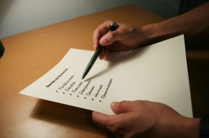 A person holds a pen and a printed checklist on a sheet of paper at a wooden desk—perfect for home service business owners who prioritize Service Excellence.