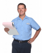 A smiling electrician in a blue uniform holds a clipboard and looks into the camera.