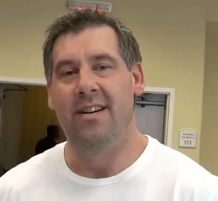 A man with short dark hair and a trimmed beard, wearing a white shirt, stands indoors facing the camera. He is one of the skilled electricians recognized for his expertise among Service Professionals.
