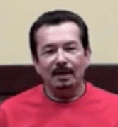A man with short dark hair and a goatee sits in front of a beige and dark brown background. He wears a red shirt and looks like one of the skilled Service Professionals you can trust for your home's needs.