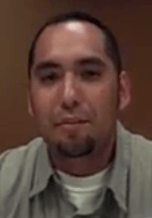 A man with short dark hair, a trimmed goatee, and a light shirt sits in front of a brown background and looks directly at the camera. He could easily pass for an experienced electrician or plumber.