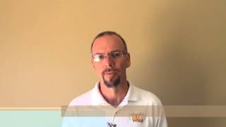A man with glasses, a goatee, and a white collared shirt stands in front of a plain beige wall. He presents the professional look common among Service Professionals such as HVAC technicians and electricians.