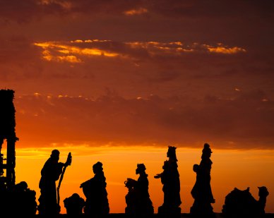 HVAC technicians and electricians move in procession, their silhouettes outlined against an orange sunset sky streaked with scattered clouds.