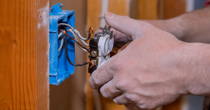 electrician repairing an electrical outlet in a home