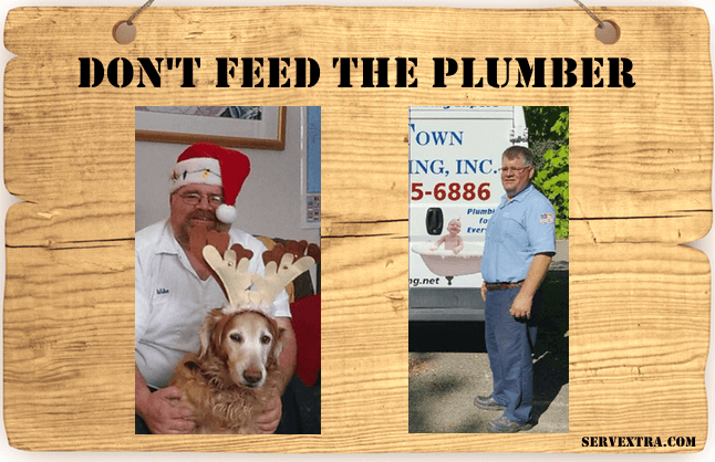 A wooden sign reads "DON'T FEED THE PLUMBER" and displays two photos of a man: one shows him in a festive hat with a dog; the other shows him as a plumber in his work uniform beside a van.