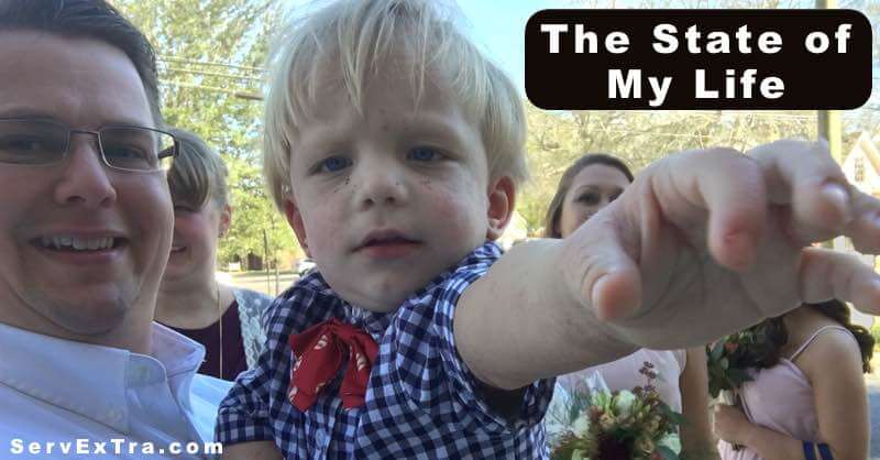 A young boy in a checkered shirt points at the camera. He stands outdoors among adults—possibly electricians or plumbers. The text reads: "The State of My Life.