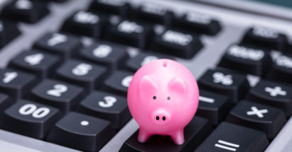Close-up Of Small Pink Piggy Bank On Calculator