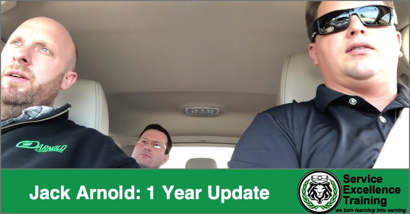 Three men sit in a car—two in front, one in back—while a green banner along the bottom reads “Jack Arnold: 1 Year Update.” The Service Excellence Training logo for professional plumbers appears on the image.