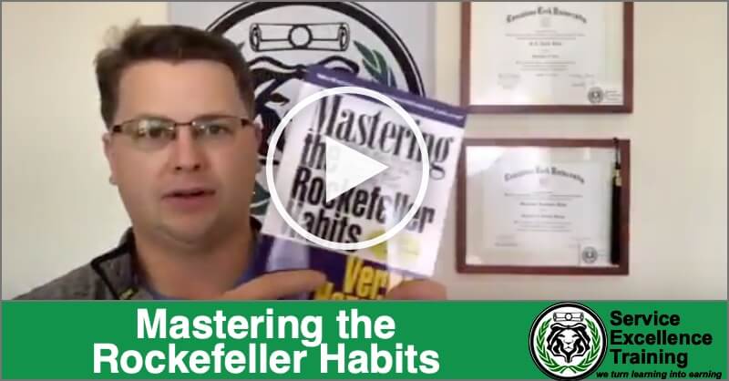 During an online training session for plumbers and HVAC technicians, a man holds up the book "Mastering the Rockefeller Habits," with certificates and the Service Excellence Training logo visible.