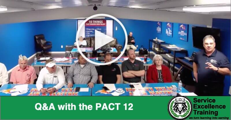 Plumbers and HVAC technicians sit around a conference table, taking part in a Q&A session. One man stands and speaks to the group. The text “Q&A with the PACT 12” appears at the bottom.