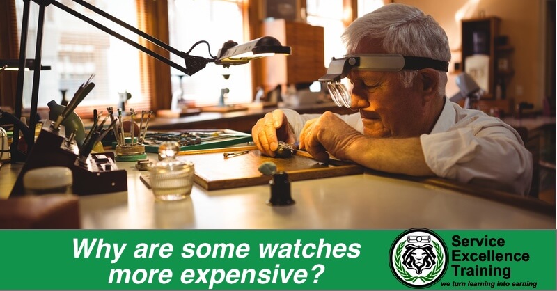 An elderly man repairs a watch in his workshop, using magnifying glasses and surrounded by watchmaking tools—just as electricians or plumbers use their own specialized equipment. The text reads: "Why are some watches more expensive?" alongside a training logo.