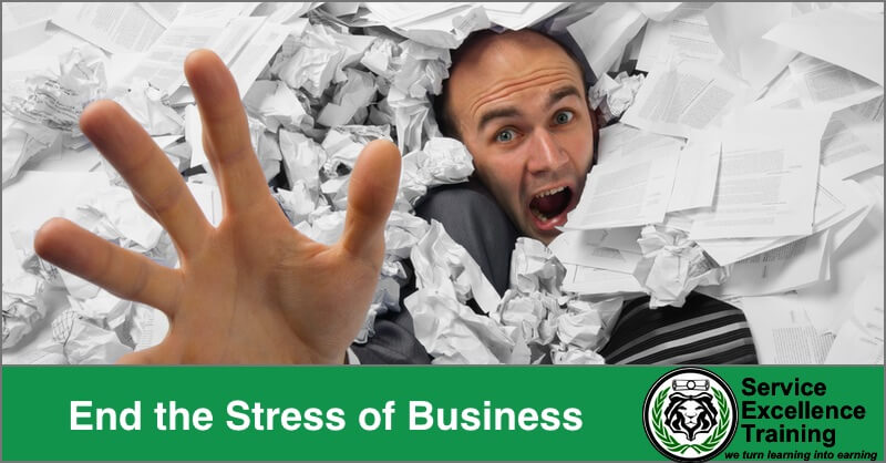 A man reaches out, overwhelmed by a pile of crumpled and scattered papers. The text says: "End Business Stress. Get Service Excellence Training and Coaching.