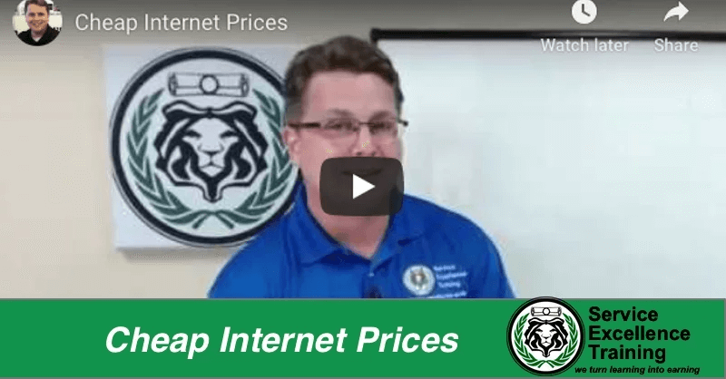 A man in a blue polo shirt stands in front of a lion logo sign. The text says, "Cheap Internet Prices" and "Service Excellence Training," promoting coaching for home service business owners.