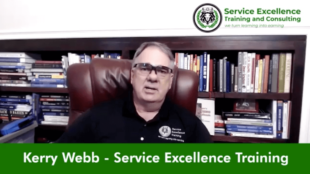 A man wearing glasses and a black polo shirt sits in an office chair with bookshelves behind him. The text, "Kerry Webb - Service Excellence Training," showcases his expertise in coaching for outstanding home services.