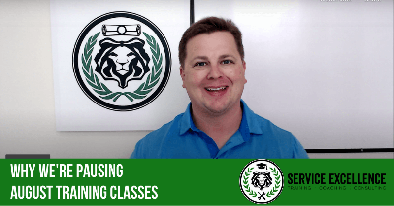 A man in a blue shirt stands in front of a lion logo. The text says: "We are pausing August training classes. Service Excellence provides training, coaching, and consulting for home service business owners.