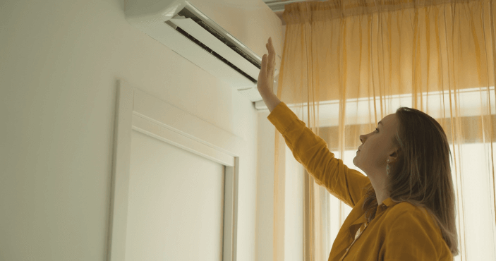 woman checking the airflow of her AC unit