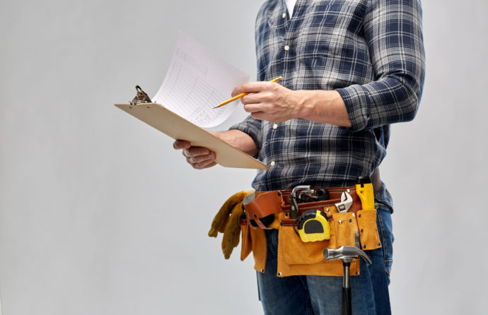 builder with clipboard, pencil and working tools