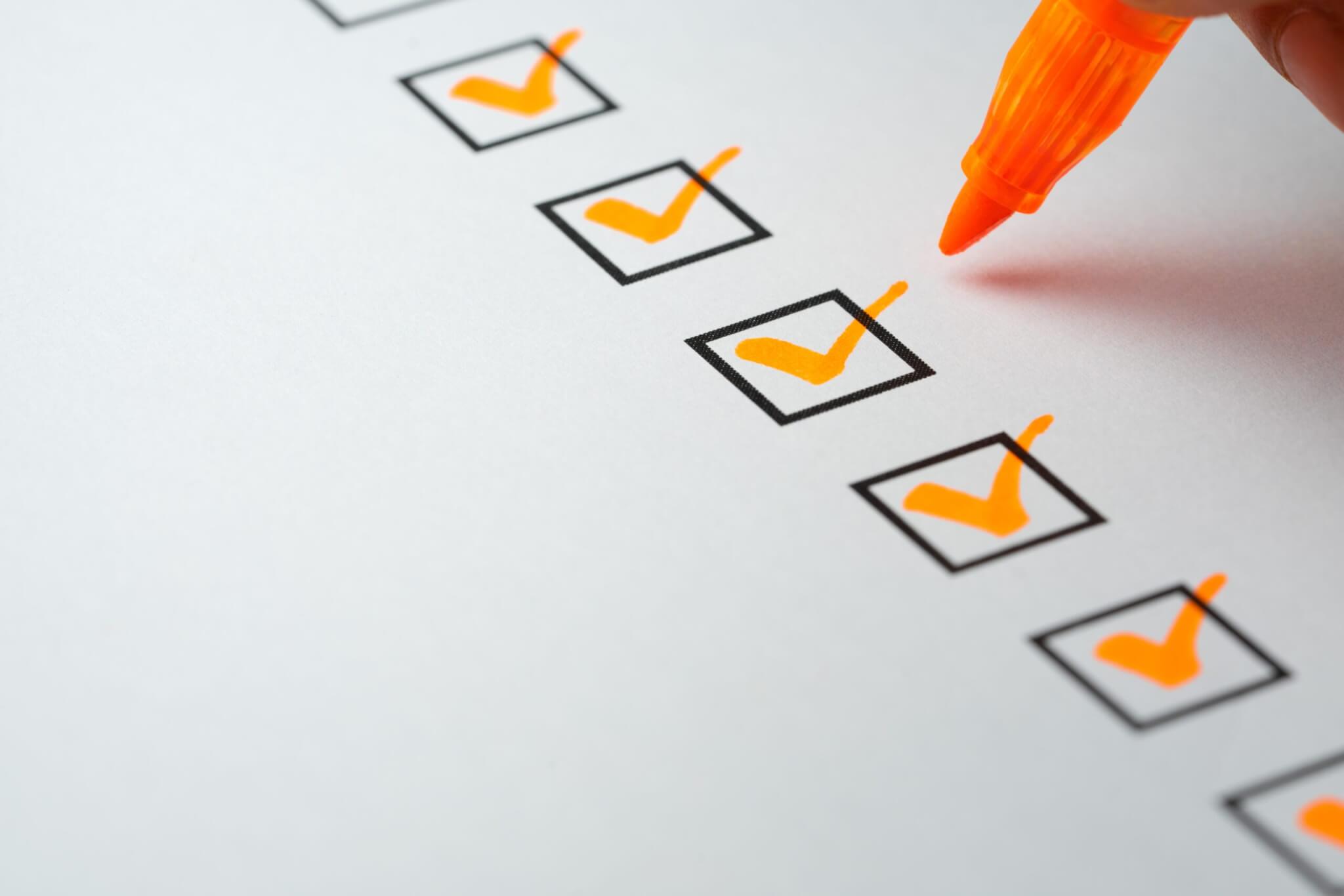 A hand uses an orange marker to place checkmarks in a series of checkboxes on a white sheet of paper, symbolizing Service Excellence in home services.