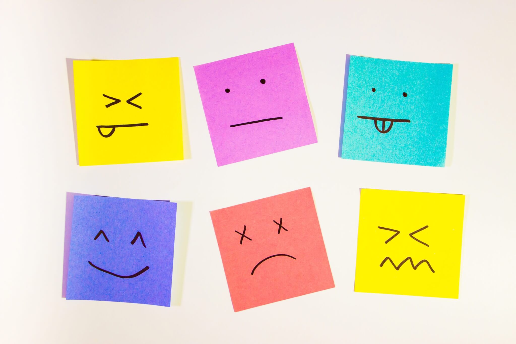 Six colorful sticky notes each show a hand-drawn facial expression, representing different emotions, on a white background. Use them to spark discussion during coaching or service training sessions for home service business owners.