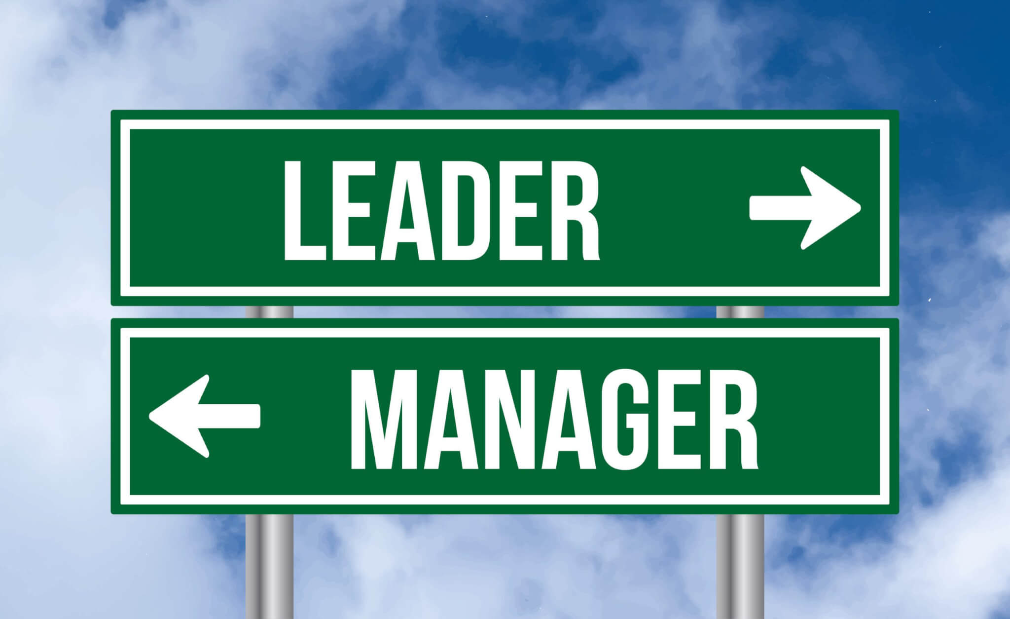 Two green directional signs stand against a blue sky. One points right and reads "Leader;" the other points left and reads "Manager." These signs represent different paths in coaching and service training for home services professionals.
