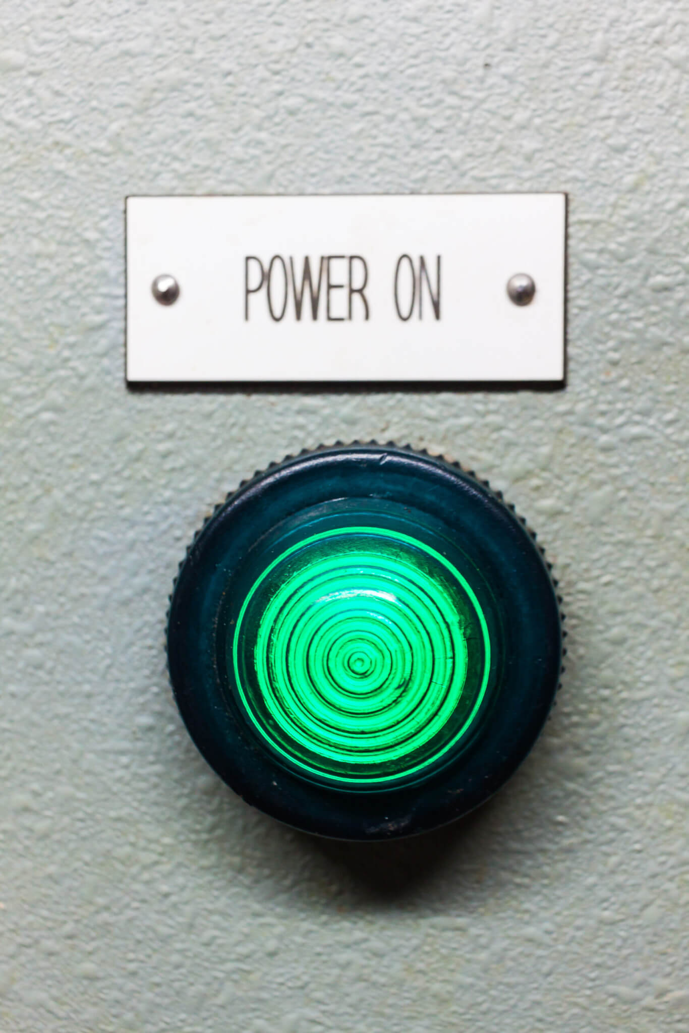 A green indicator light glows below a "POWER ON" sign on a textured gray surface, signaling that home service business owners are ready to energize their operations.