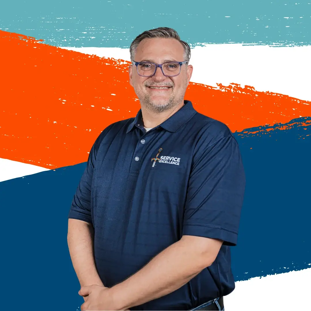 A smiling man in glasses and a navy blue polo shirt stands confidently in front of a colorful abstract background, embodying Service Excellence—the core value of leading home service business owners.