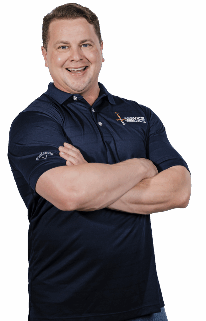 A man in a navy blue polo shirt stands with his arms crossed and smiles.